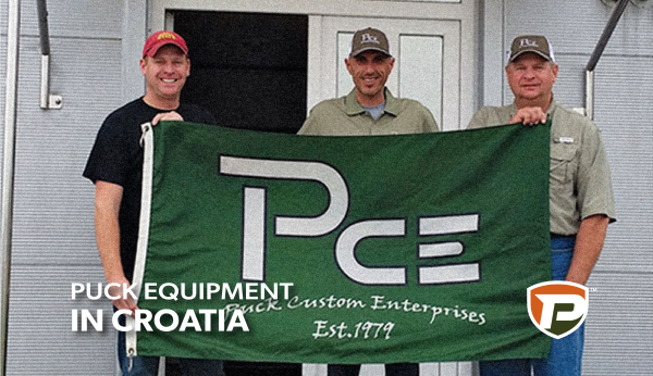 Ben and Jeremy Puck on each end of the PCE flag and standing with another man in the center at the Croatia location with the title reading Puck Equipment in Croatia