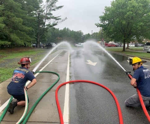 two firefighters crouching and spraying water from hoses