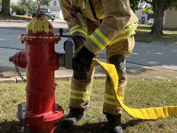 a firefighter connected the Ultima fire hose to the U.S. Coupling manifold attached to the arm of a fire hydrant on a street corner