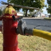 a fire hydrant with a wrench sitting on top and a U.S. Coupling manifold attached to an arm with the crank open to allow water into the Ultima hose connected