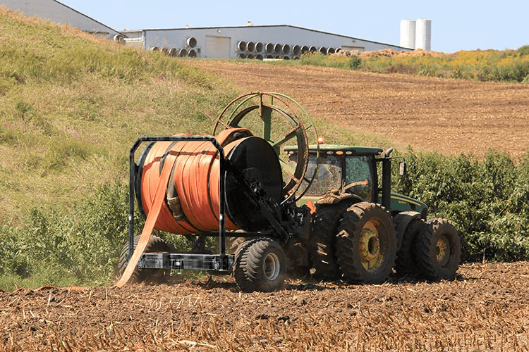 Hose cart with Drag Hose and hose mover attached to a tractor moving through a field