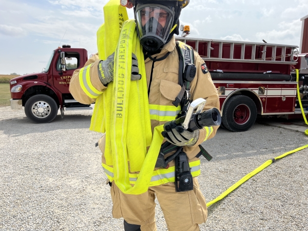 a firefighter carrying the crosslays of Firepower fire hose from the fire truck
