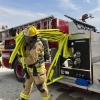 a firefighter in full gear pulling Firepower II crosslay hose off a fire truck
