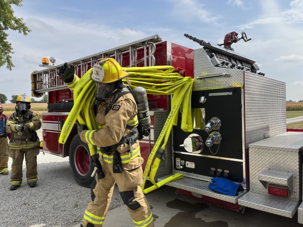 a firefighter in full gear pulling Firepower II crosslay hose off a fire truck