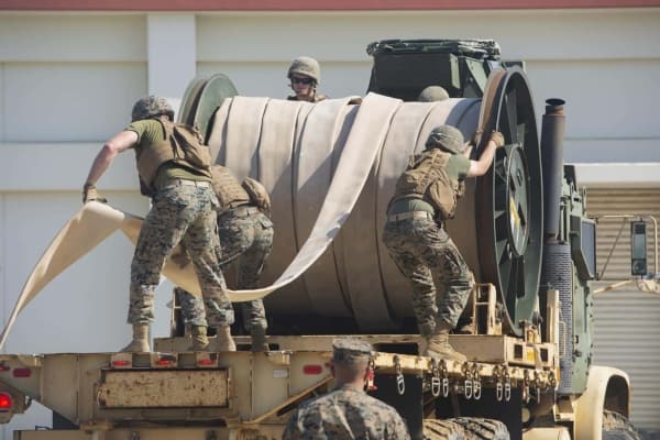 R4H8RX Marines with Bulk Fuel Company, 9th Engineer Support Battalion, 3rd Marine Logistics Group, unreel a fuel hose from the back of a Medium Tactical Vehicle Replacement 7-ton truck during fuel support operations training Oct. 2, 2018 at Camp Hansen, Okinawa, Japan. The Marines unrolled the hose to connect the fuel site and the fuel pump to distribute water, which is used during training evolutions instead of fuel, through the lines. The bulk fuel specialists assembled fuel sites at Camp Hansen in order to practice fueling support operations for upcoming exercises and deployments.