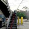 a firefighter on the exterior stairs of a building, crouched and using the red Firepower II hose