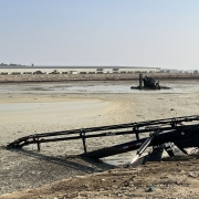 a Puck Lagoon Feeder on the shore of a manure lagoon with a Puck agitation boat in the lagoon in the distance