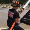 the back of a firefighter who is crouching on the ground and spraying water from the hose he holds