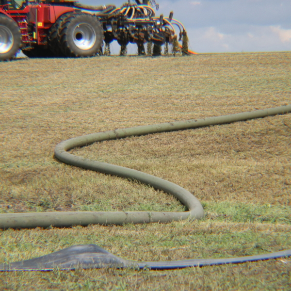 mainline hose on a hill leading to an applicator tractor with toolbar