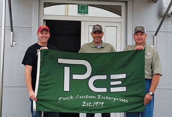 3 men holding a PCE flag and standing in front of the new Croatia location