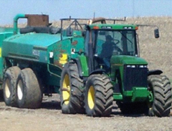 a tractor pulling a green barrel
