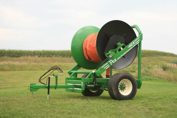a green HC8 sitting in the grass with an orange hose
