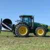 side view of a tractor and a Puck HR 4 3PT hose reel on a tractor with black hose on the reel