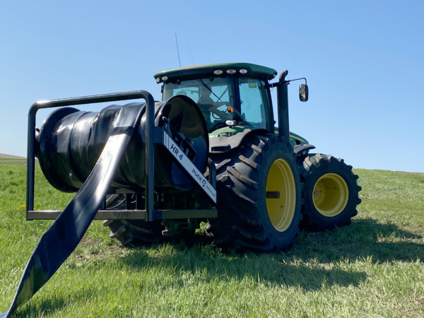 back passenger side view of a Puck HR 4 3PT hose reel on a tractor with black hose on the reel