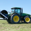 a side view of a Puck HR 4 3PT hose reel on a tractor with black hose on the reel