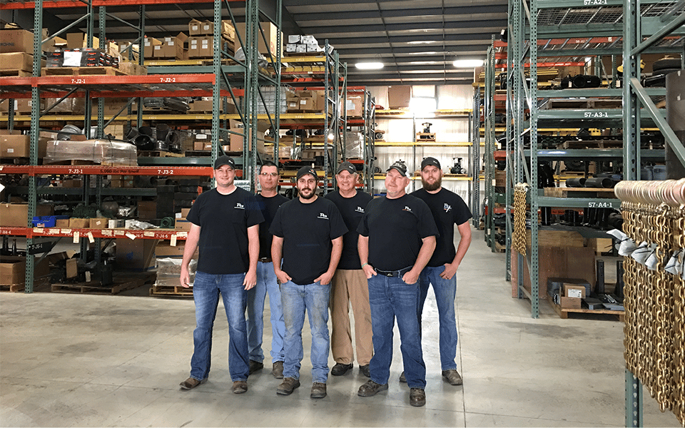 the six employees who make up the parts department standing together in the parts warehouse