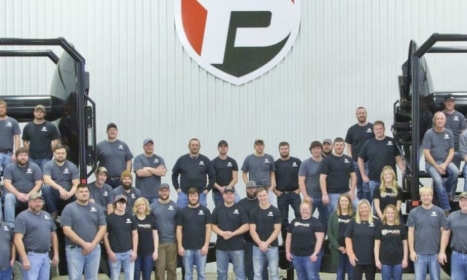 a group shot of Puck employees in front of the warehouse and some hose carts