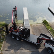 a white pickup truck towing a FF4500-45 and backed up to a lake. the Force Feed trailer has extended outriggers and boom with attached hose lines