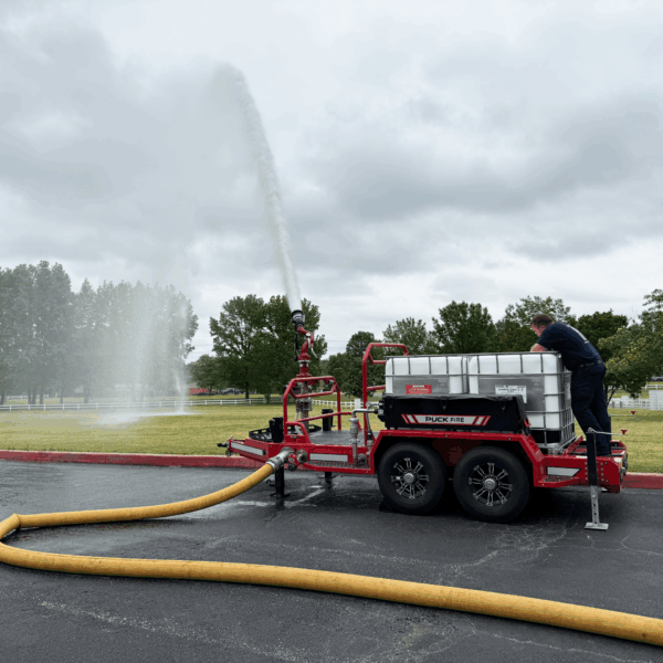 Foam tote trailer with connected supply hose spraying water into field