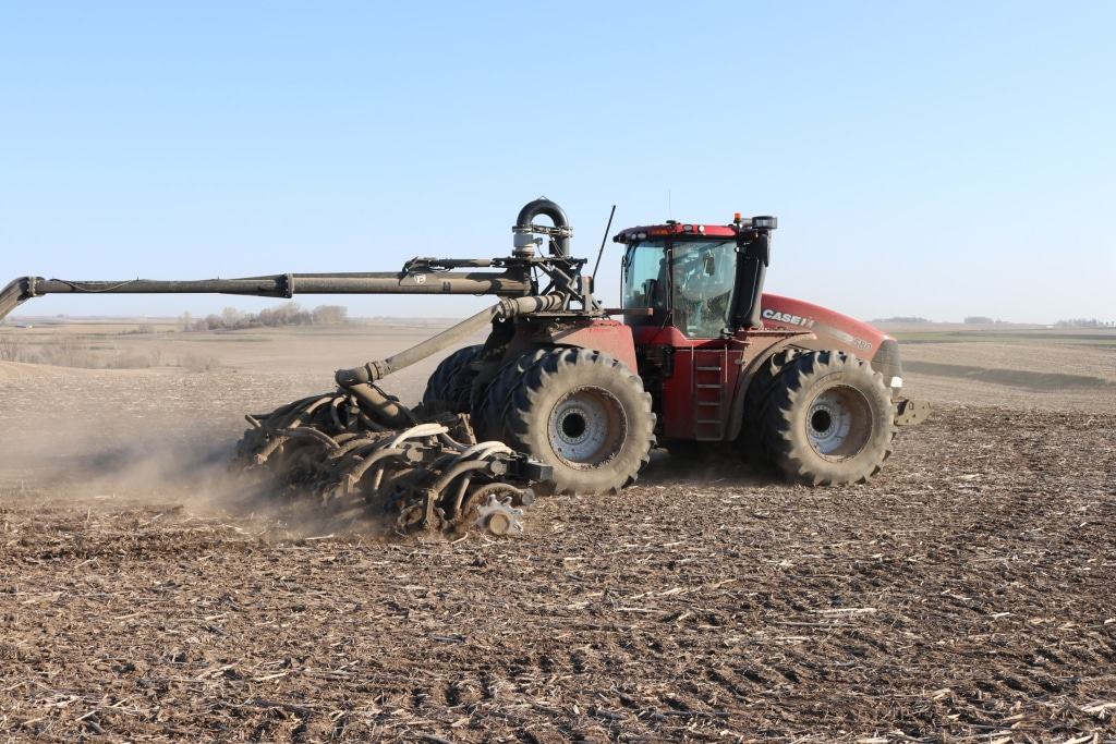 side view of a torsion flex toolbar in use behind a tractor in a field kicking up dirt. the toolbar and tractor are connected through the 4WD mounted swingarm