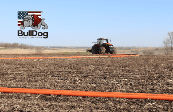 tractor with hose mover in distance laying orange drag hose in field