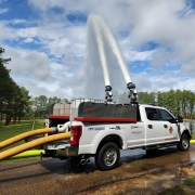 a Quick Attack Truck with foam tote in the bed and connected to hoses spraying water with foam injection into pond