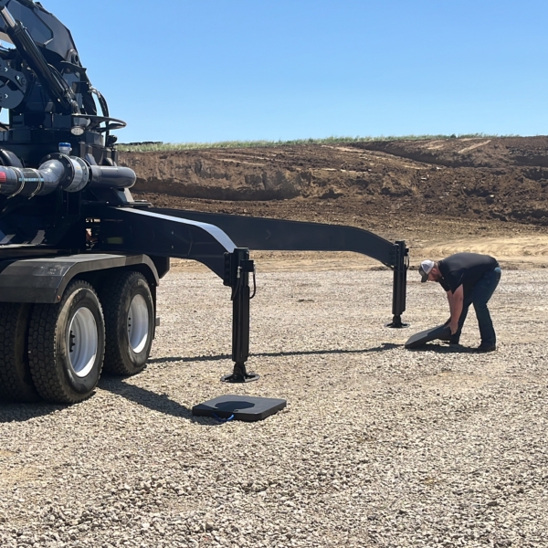 man sliding a Cope Plastics outrigger pad under a Puck Boom truck outrigger