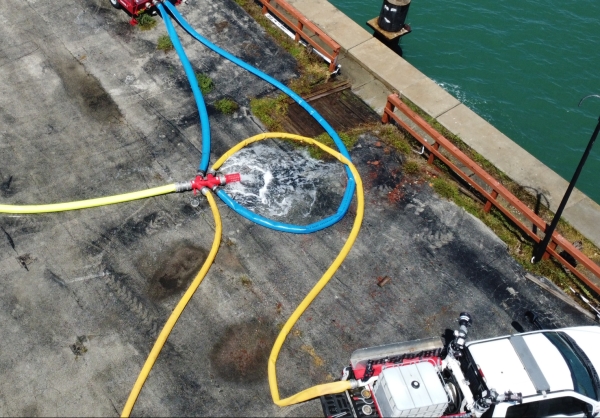 five hoses connected to a manifold with a cage on one end to catch the foam pigging ball when it reaches the end of the line, water is rushing out of the cage as the line is cleared