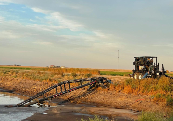 a lagoon feeder sitting on the back of the lagoon as it agitates and is connected via hose to a pump trailer