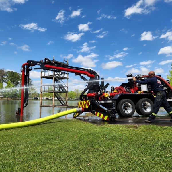 man using handline with water from Puck Fire FF4500-45 force feed trailer with connected Hi-Vol TPU XLDH supply line drafting water from pond