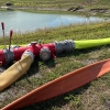 a U.S. Coupling manifold and attached pig catcher on the ground with hoses attacked next to a pond. the cage has water pouring out from the line being purged