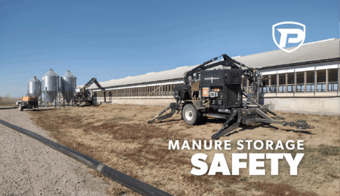 two agitation trailers with hydraulic booms extended into the manure agitation pits of a barn