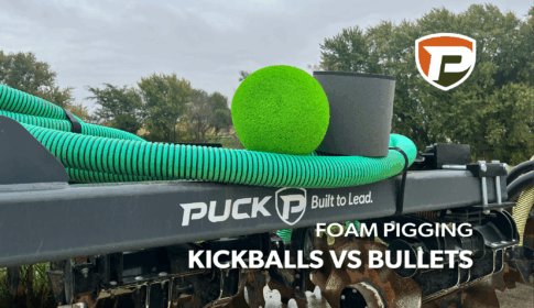 a green foam kickball and gray foam bullet sitting on top of a manure injection toolbar with the overlaid title reading Foam Pigging Kickballs vs Bullets