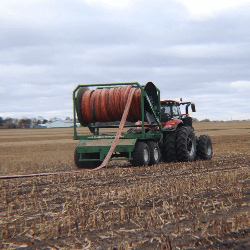a red tractor pulling the first Puck TTR 20 through a field as it lays hose