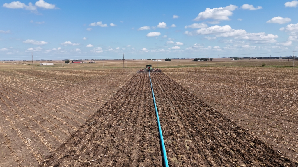 an application tractor pulling an X24 drag hose and manure injection toolbar across a field
