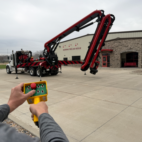 a Puck Fire FF4000-70 with extended outriggers extending the hydraulic boom with a remote control at a distance